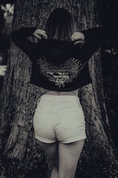 Stylish black and white fashion photo of woman in outdoors setting wearing jacket and shorts.