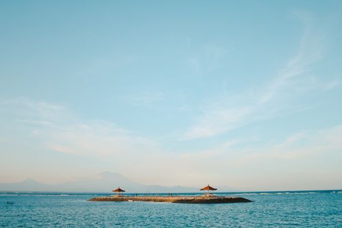 Free Tranquil island view with blue sky and calm ocean waters, perfect for relaxation imagery. Stock Photo