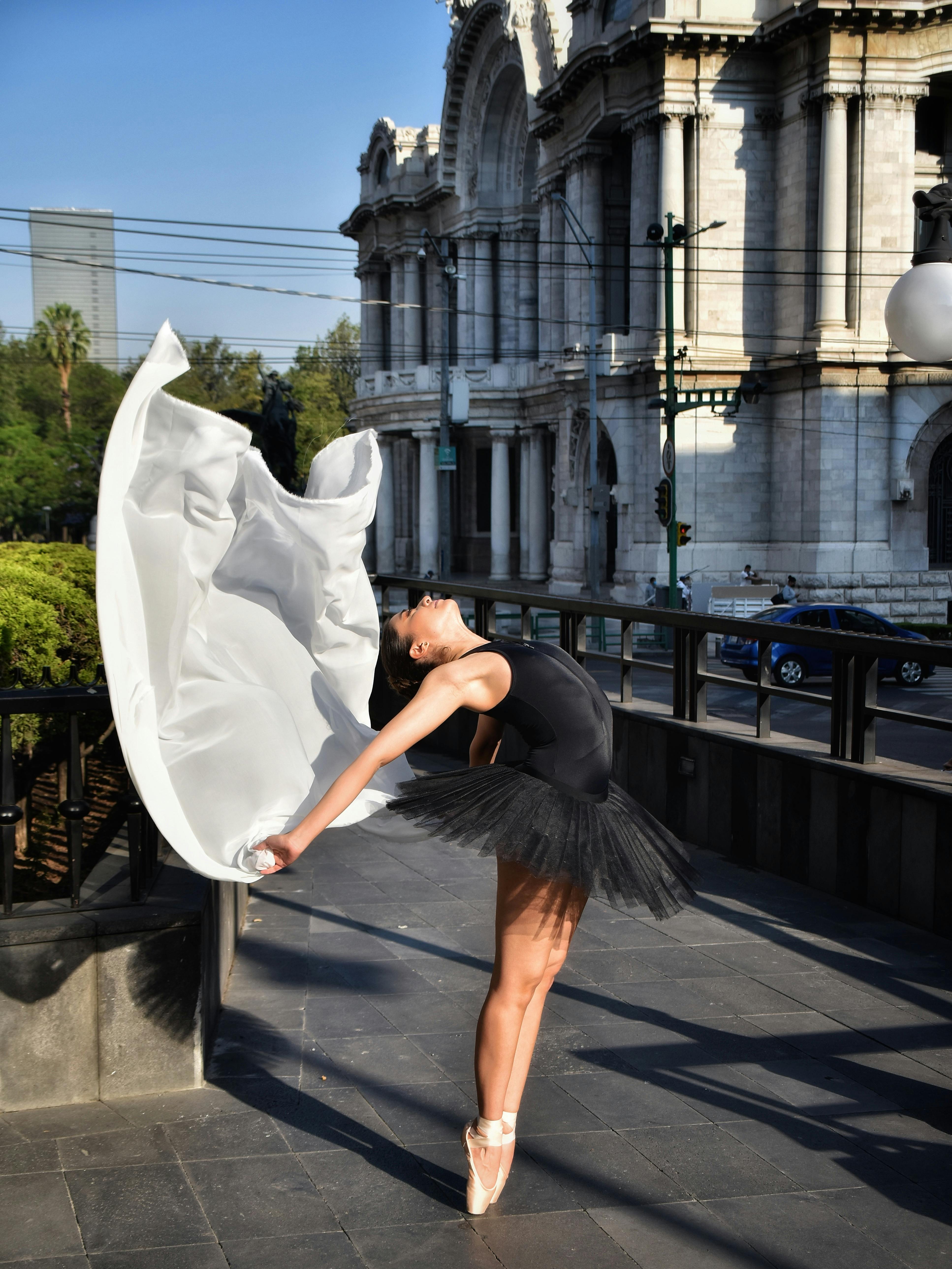 Ballet dancer performing gracefully in front of the iconic Palacio de Bellas Artes in Mexico City.
