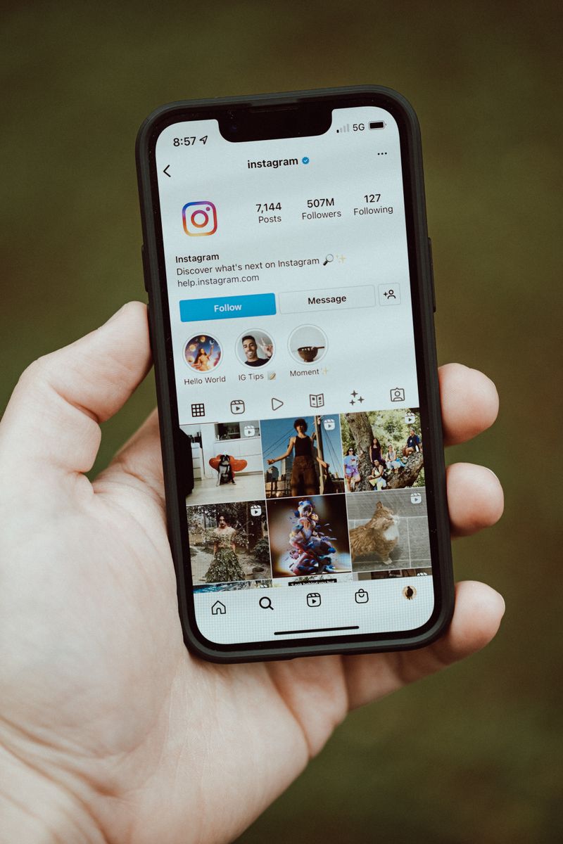 A close-up of a hand holding a smartphone showing an Instagram profile app screen