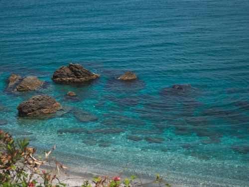 Free Scenic view of a tranquil rocky shoreline with clear blue ocean waters and visible rock formations. Stock Photo