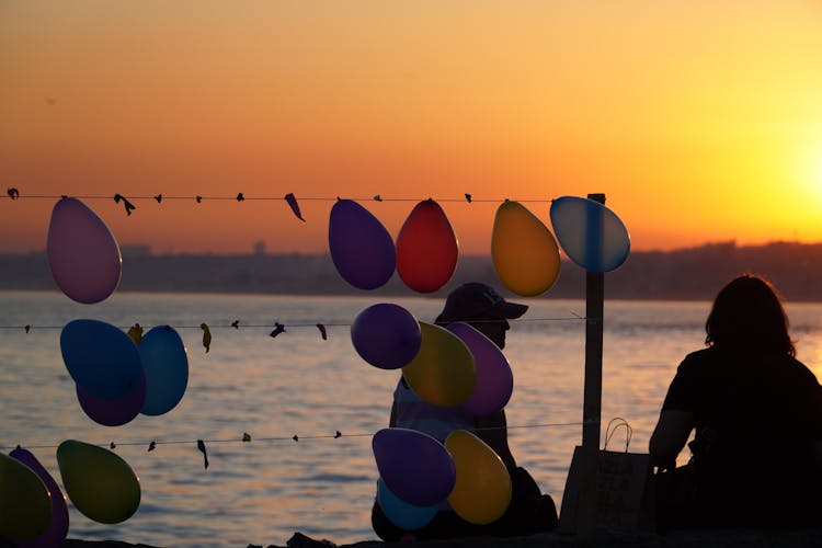 Two People Sitting Near Balloons Party At Dusk