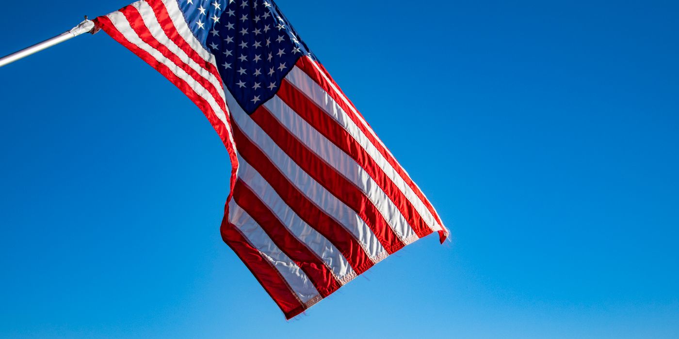 The American flag proudly waves on a flagpole against a clear blue sky, symbolizing freedom and patriotism.