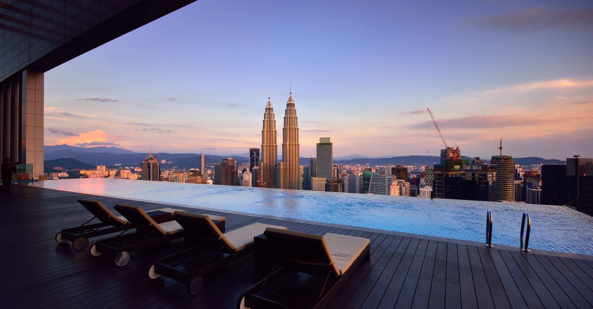 Relax by a luxury infinity pool with stunning Kuala Lumpur skyline and Petronas Towers at twilight.