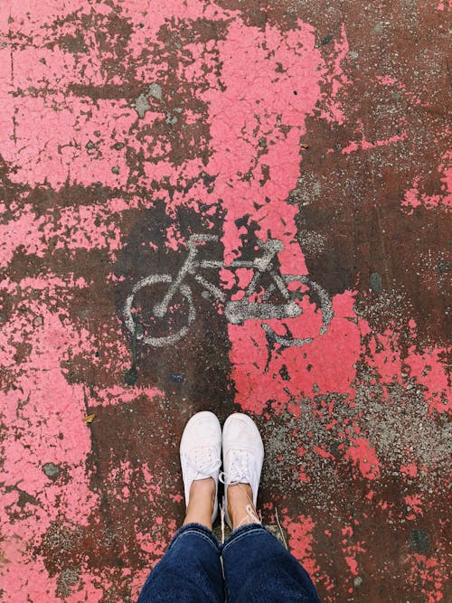 Person's Feet on Bicycle Artwork With Pink Background