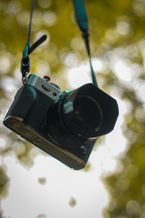 Free Artistic close-up of a hanging vintage camera with a blurred nature background, ideal for photography themes. Stock Photo