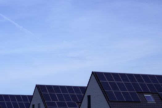 Modern Belgian houses with solar panels on rooftops under a clear blue sky.