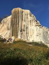 Group of People on Green Grass Field Near Brown Rock Formation Under Blue Sky