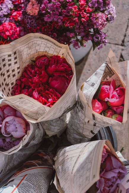 Colorful peony bouquets wrapped in newspaper, creating a rustic floral display.