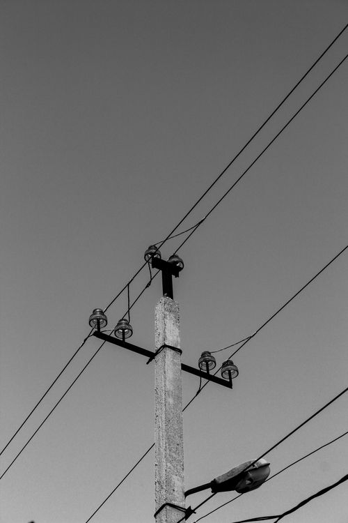 Free Monochrome image of a towering transmission pole and wires against the sky. Stock Photo