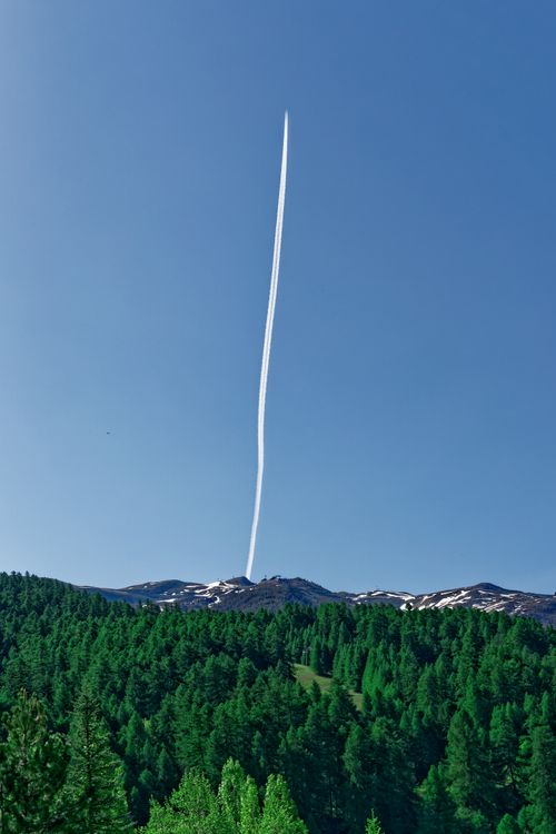 Free A striking contrail in a clear blue sky above a dense green forest in Provence, France. Stock Photo