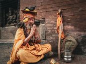 Man in Brown Thobe Sitting on Ground