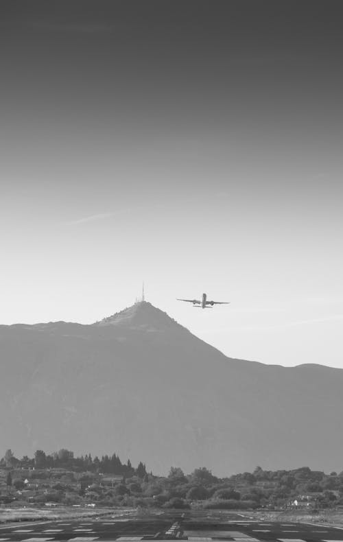 Airplane Flying Near Mountain inn Grayscale Photography 
