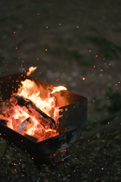 Free Close-up of outdoor barbecue fire with glowing embers and sparks on a cool night. Stock Photo