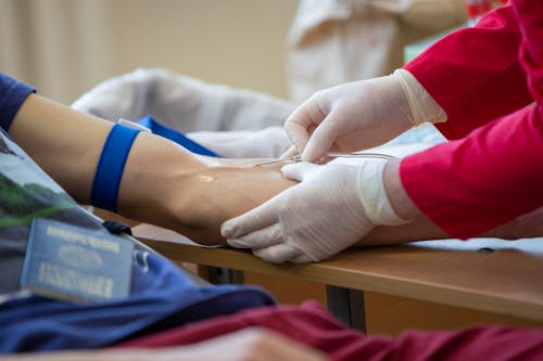 A Medical professional Inserting Needle to s Person's Arm