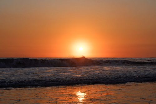 Free A breathtaking sunset over the ocean with waves crashing on the shore. Stock Photo