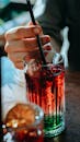 Person Holding Black Pen and Clear Drinking Glass With Red Liquid