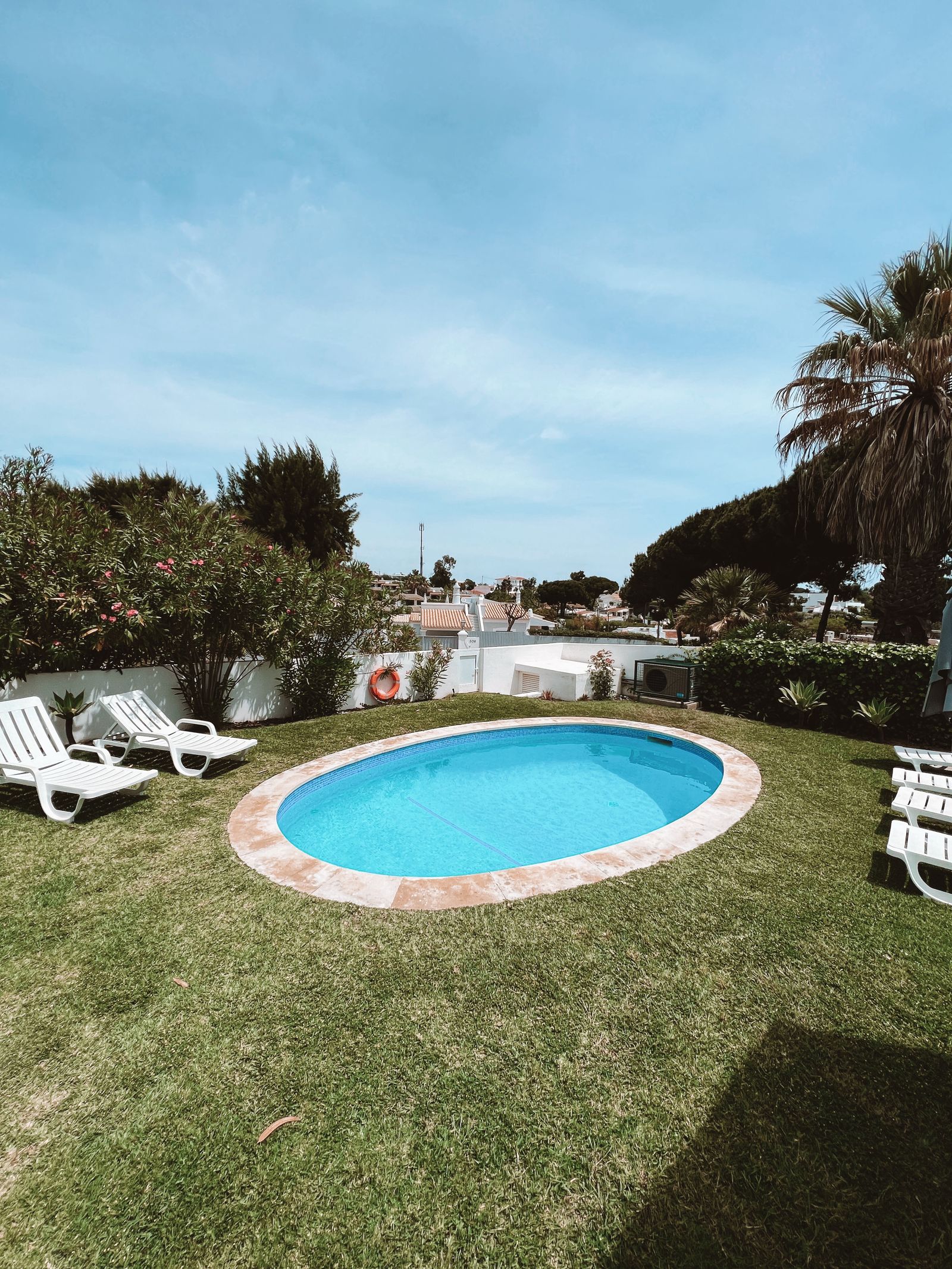 Piscina residencial con césped y cielo despejado