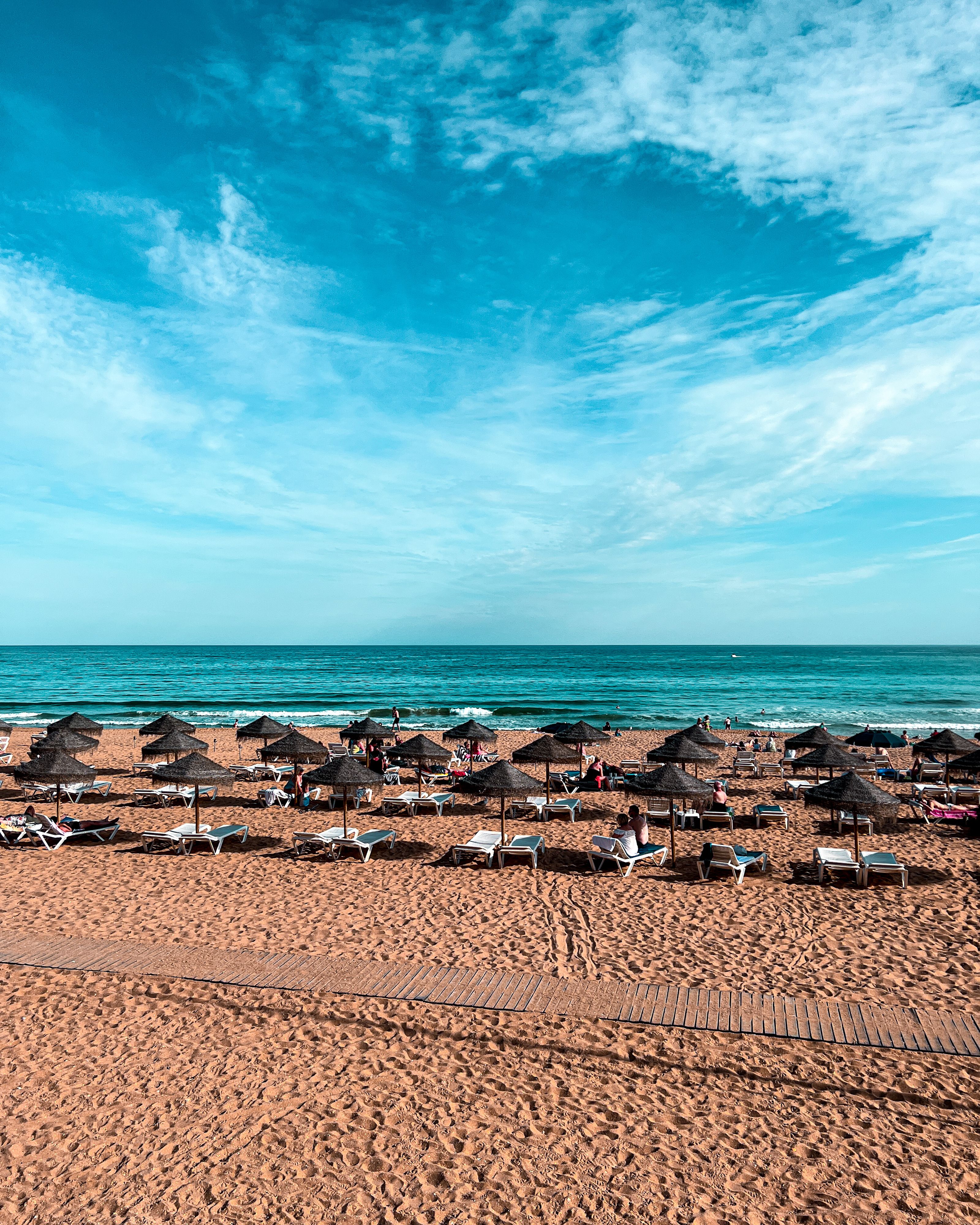 Une plage ensoleillée avec des chaises et des parasols face à la mer.