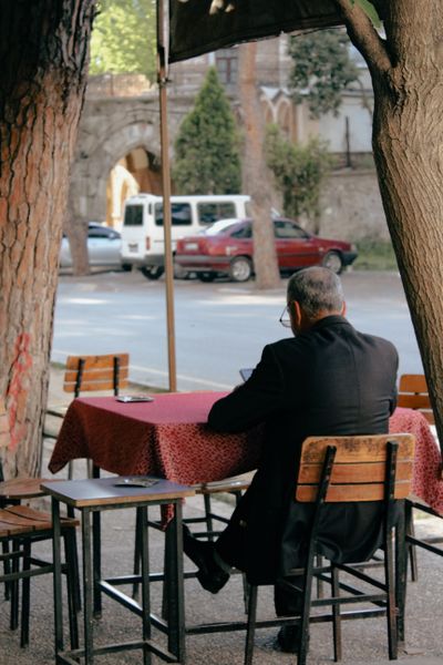 A man sitting alone at a sidewalk café on a clear day