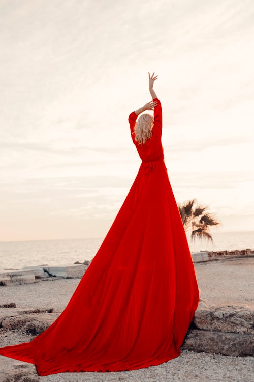 A Woman in Red Dress Standing on Seacoast