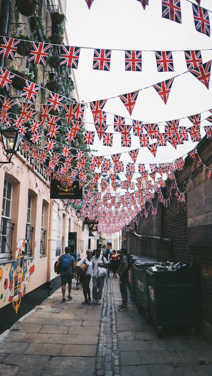 Free People Walking in an Alley with Hanging Union Jack Buntings  Stock Photo
