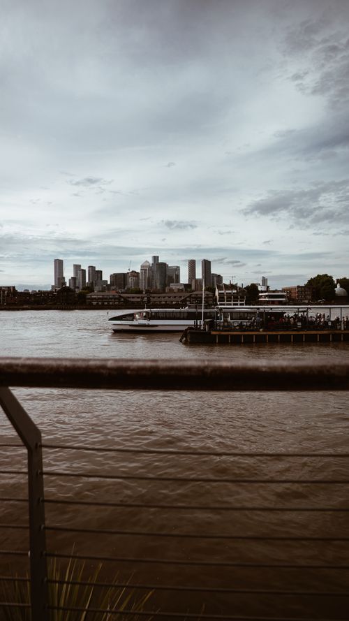 Free Urban skyline view with waterfront and ferry dock under a cloudy sky. Stock Photo