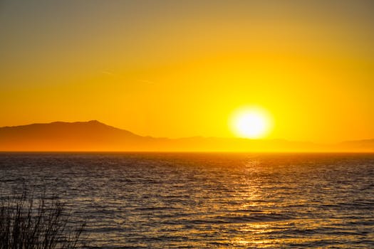 Experience the serenity of a vivid ocean sunset with golden hues illuminating the horizon.