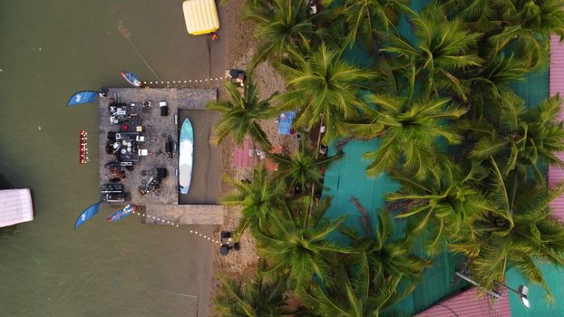 Aerial shot of a pier surrounded by palm trees and equipment setup, located in Chiang Yuen, Thailand.