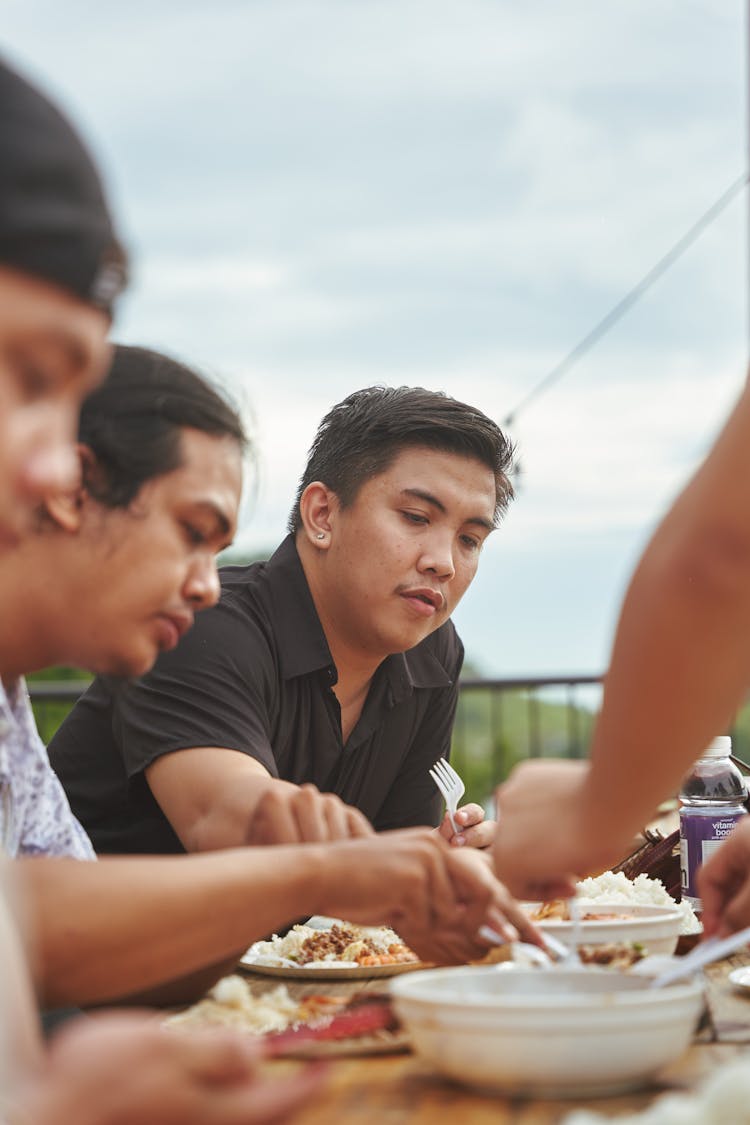 People Sitting At Table Outside Eating