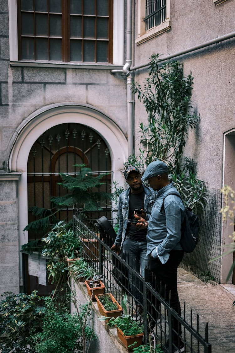 Two Men Talking On Balcony Of Old Building