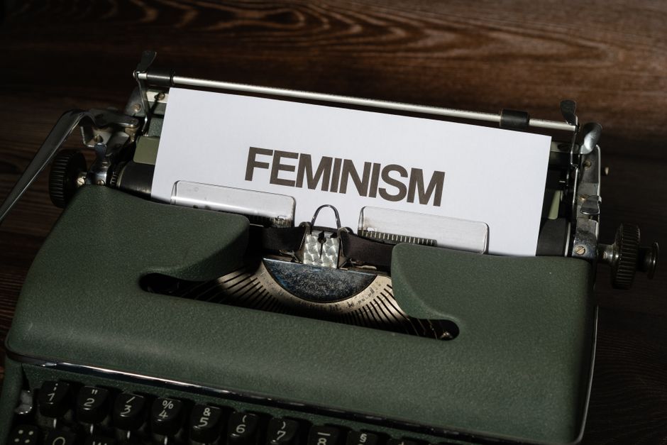Close-up of a vintage typewriter with the word feminism typed on paper, symbolizing women's empowerment.
