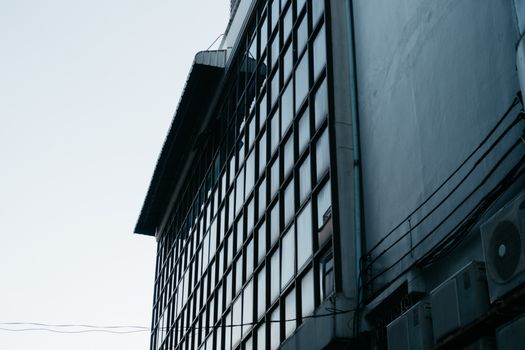 Close-up shot of a modern building with glass windows reflecting light, highlighting urban architecture.