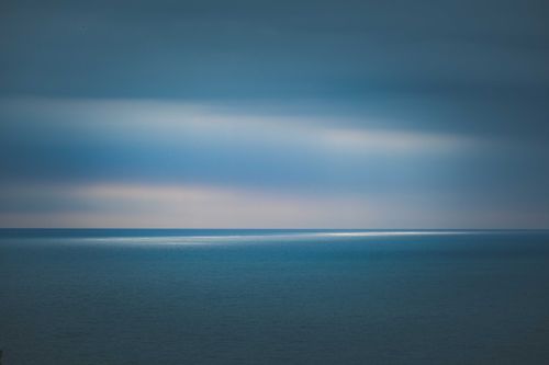 Free A serene and expansive view of the calm ocean at twilight, capturing the peacefulness of nature. Stock Photo
