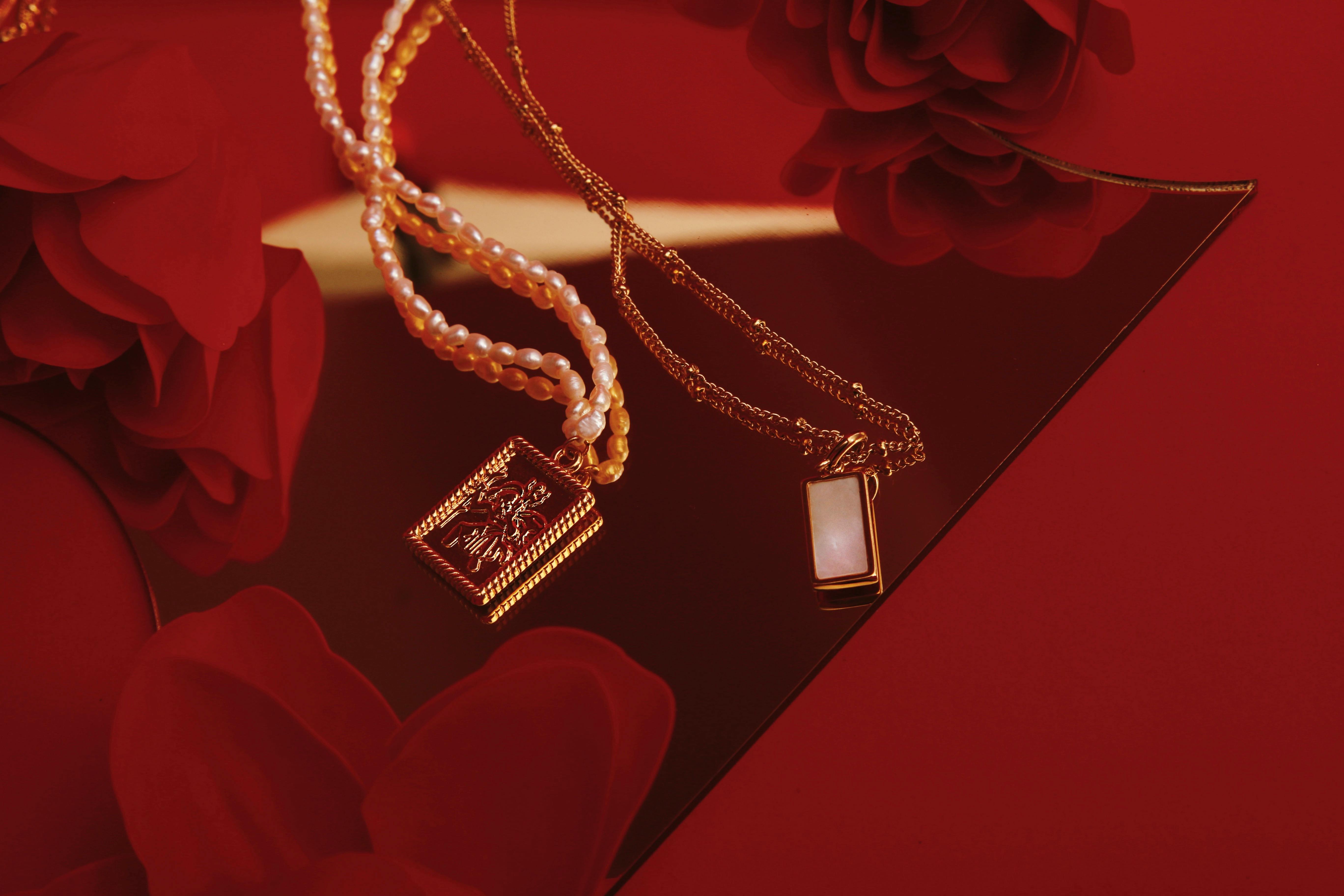 [ColoSach]-gold-and-pearl-necklaces-with-a-decorative-mirror-and-red-flowers-in-a-stylish-arrangement.