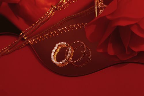 Free Beautiful pearl and gold bracelets displayed on a rich red fabric, exuding elegance and luxury. Stock Photo