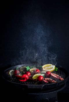 Colorful assortment of vegetables and citrus slices grilling with steam on a grill pan.