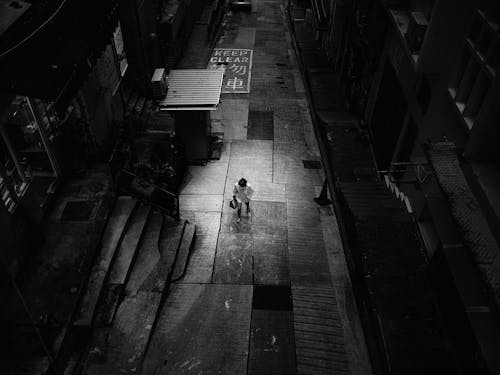 Grayscale Photography of a Person Walking on the Street