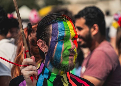 Colorful face paint at a lively LGBT pride parade in Milan, showcasing individuality and celebration.