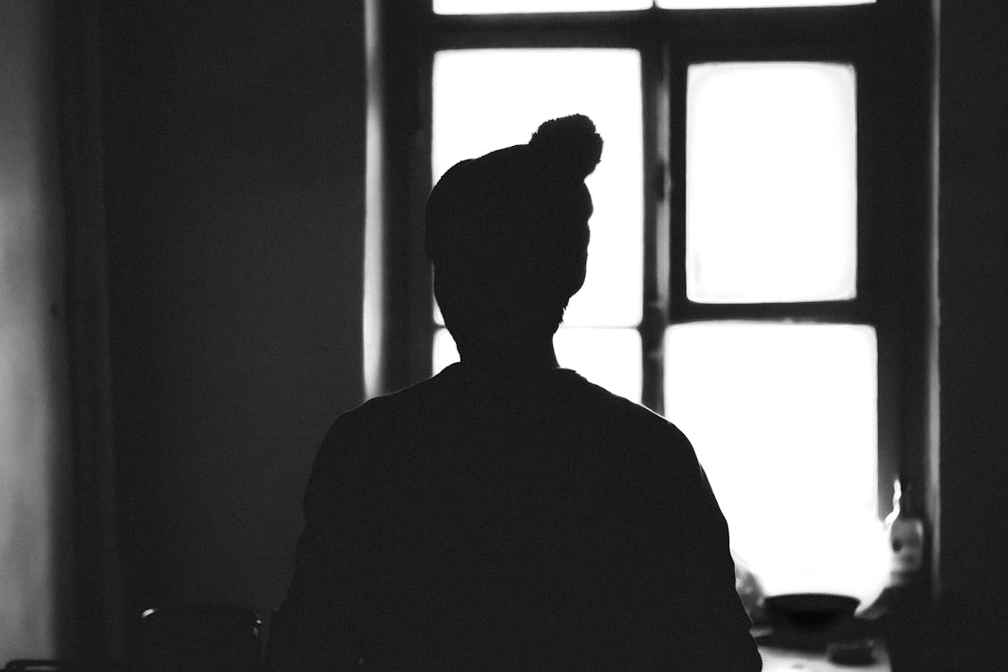 Grayscale photo of man standing near window photo – Free Cloud