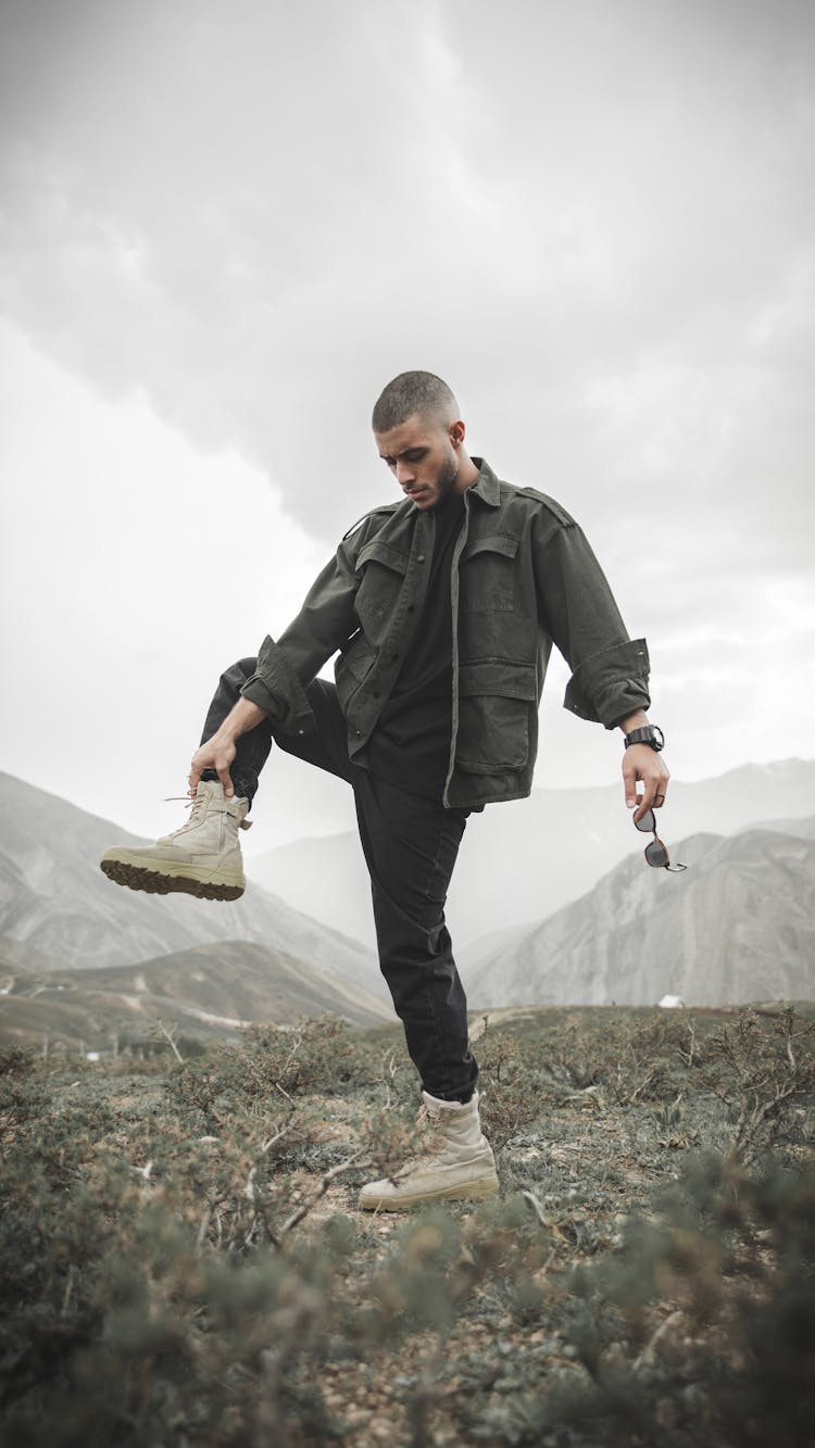 A Man Wearing Black Jacket Holding His Foot