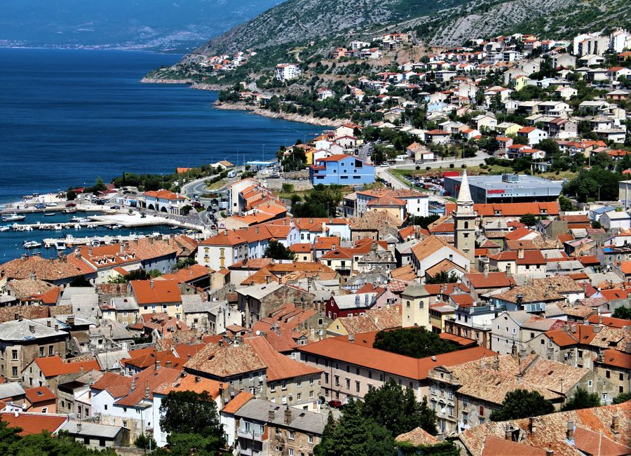 Scenic aerial view of Senj, Croatia with coastline, rooftops, and surrounding mountains.