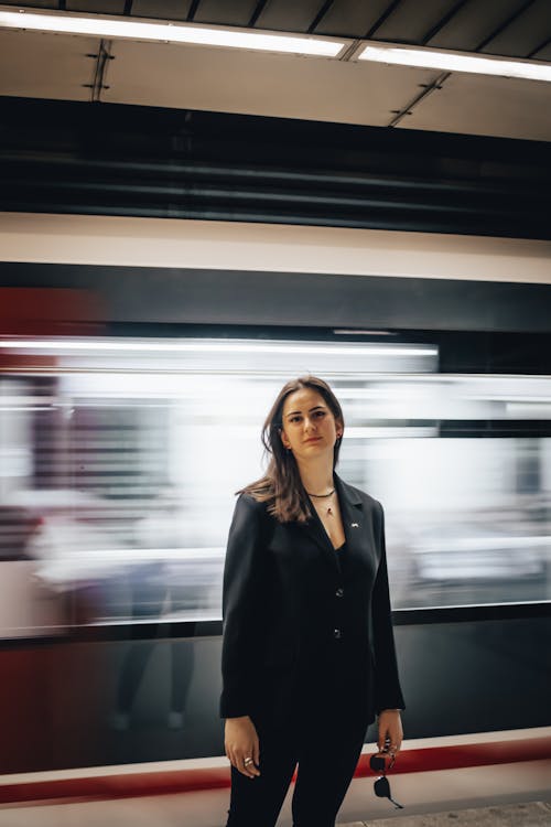A Woman in Black Blazer Standing Near the Moving Train