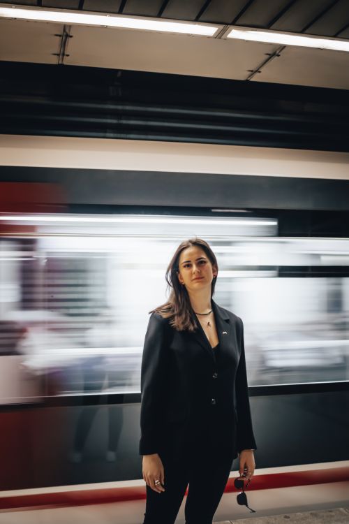 Free Woman standing confidently at İzmir train station with motion blur of passing train. Stock Photo