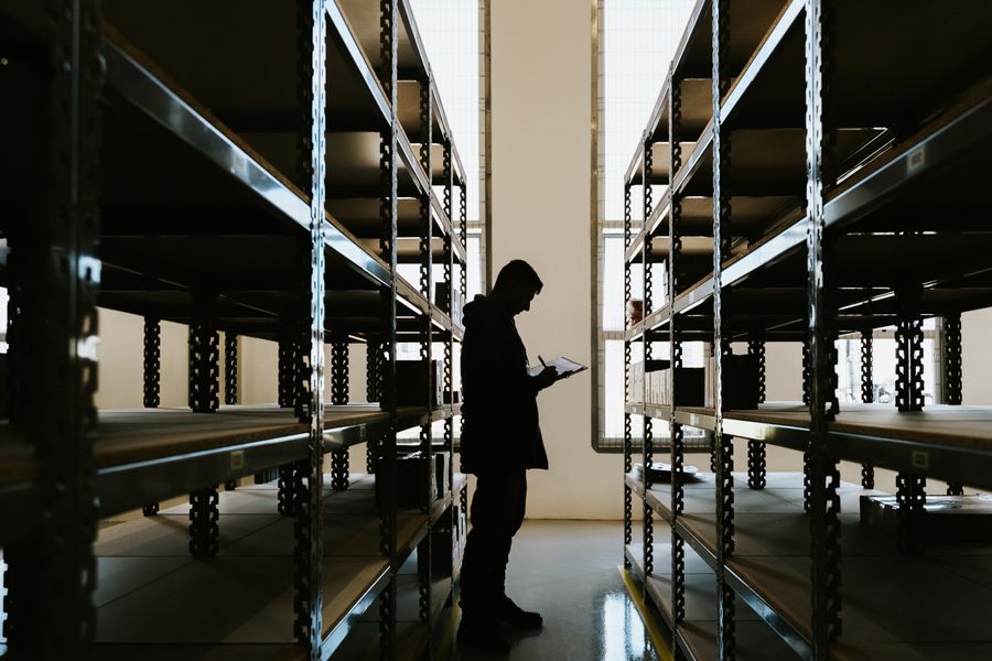 Warehouse operative checking goods against a clipboard of shipping documentation