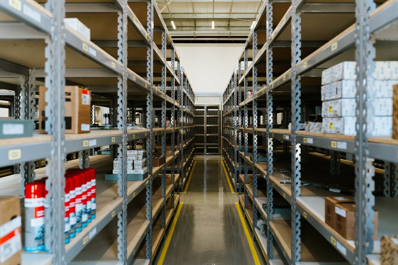An organized warehouse aisle with metal shelving — photo by Daniel Andraski on Pexels