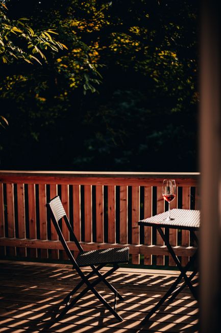 A serene patio view with a rattan chair and wine glass at sunset, casting beautiful shadows.