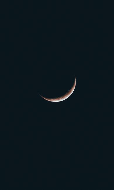 A breathtaking view of a crescent moon shining in the dark sky above Geneva, Switzerland.