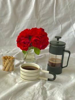 Elegant setup with coffee, red roses, and pastries on a white background. Perfect for a cozy morning.