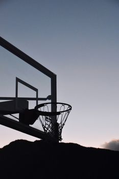 Silhouette of a basketball hoop against a serene evening sky in Colorado Springs.